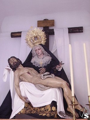El Cristo cae sobre el regazo de su madre que lo sostiene con una mano y en la otra porta los clavos con los que estuvo crucificado en la cruz 